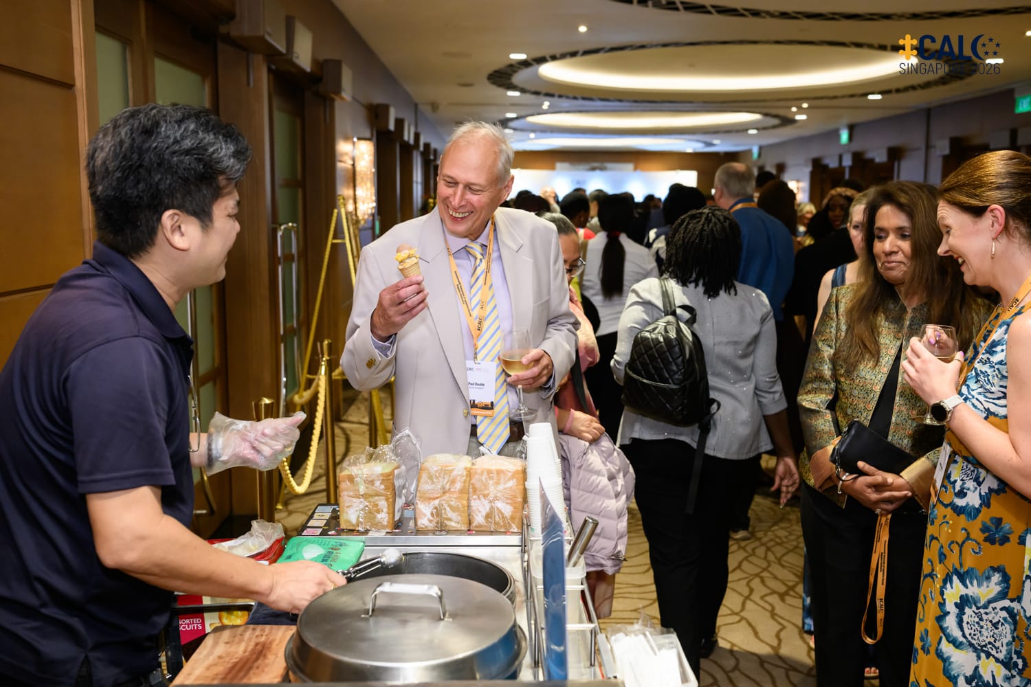A delegate laughs while holding an ice cream cone at a street food cart during the Conference networking reception at The Fullerton Hotel Singapore.
